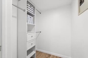 Et walk-in closet med åbne døre, hylder og skuffer.
