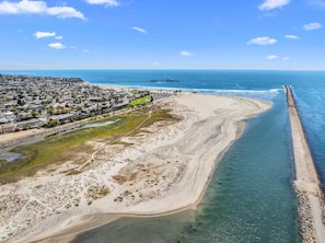 Vista aèria d'una zona costanera amb una platja, un moll i una zona residencial.