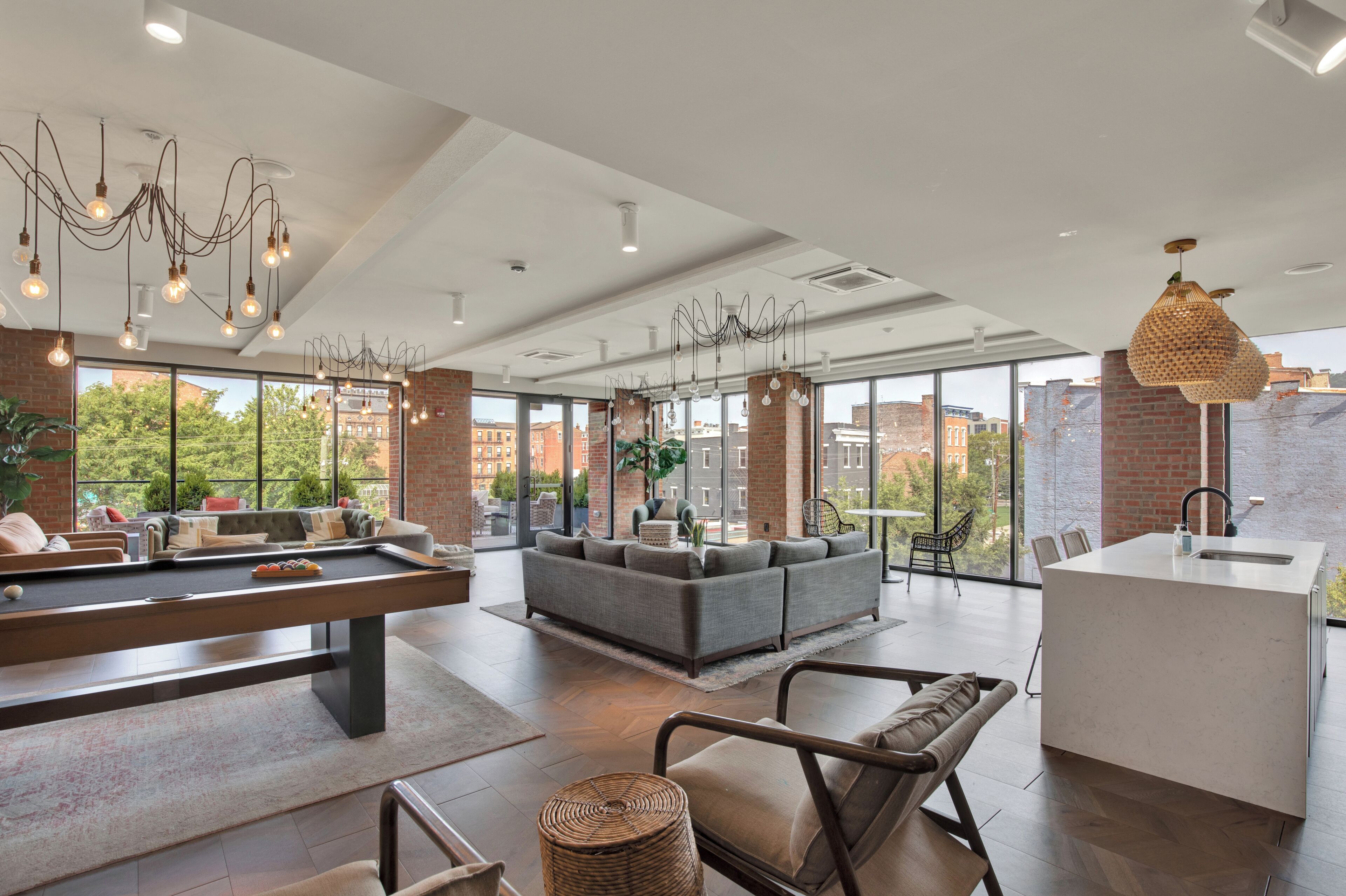 Un salón moderno con mesa de billar, zona de estar y ventanas amplias con vista a la ciudad.