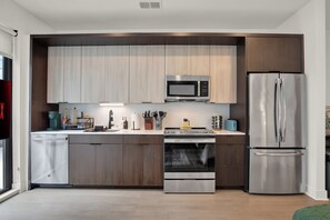 Eine moderne Küche mit Edelstahlgeräten, Holzschränken und einem eingebauten Backofen.