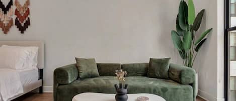 Una sala moderna con un sofá verde, una mesa de centro blanca y una planta grande.