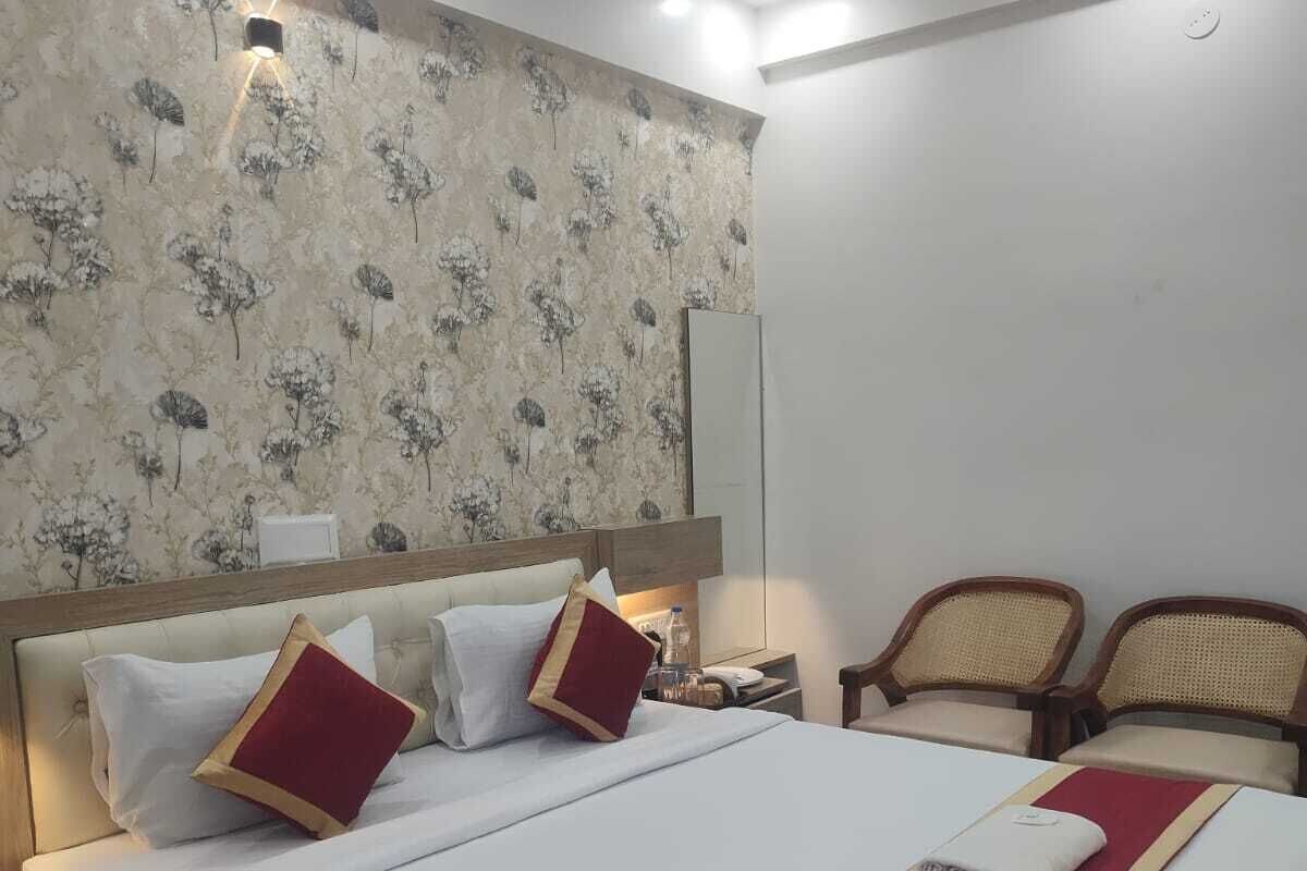 A hotel room with a bed, nightstands, a lamp, and two chairs.