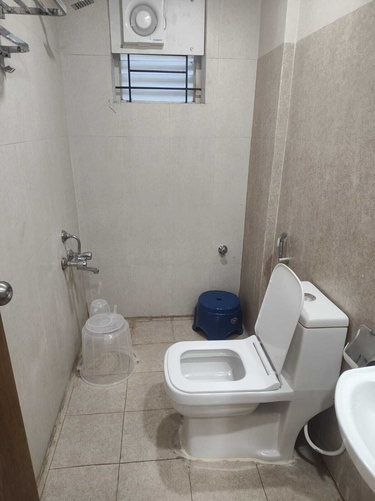 Un baño pequeño y funcional con inodoro, un lavabo azul y un tanque de agua.