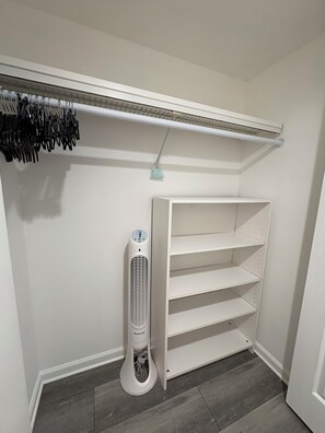 Ein weißer Schrank mit eingebautem Heizung, Kleiderstange und offenen Regalen.