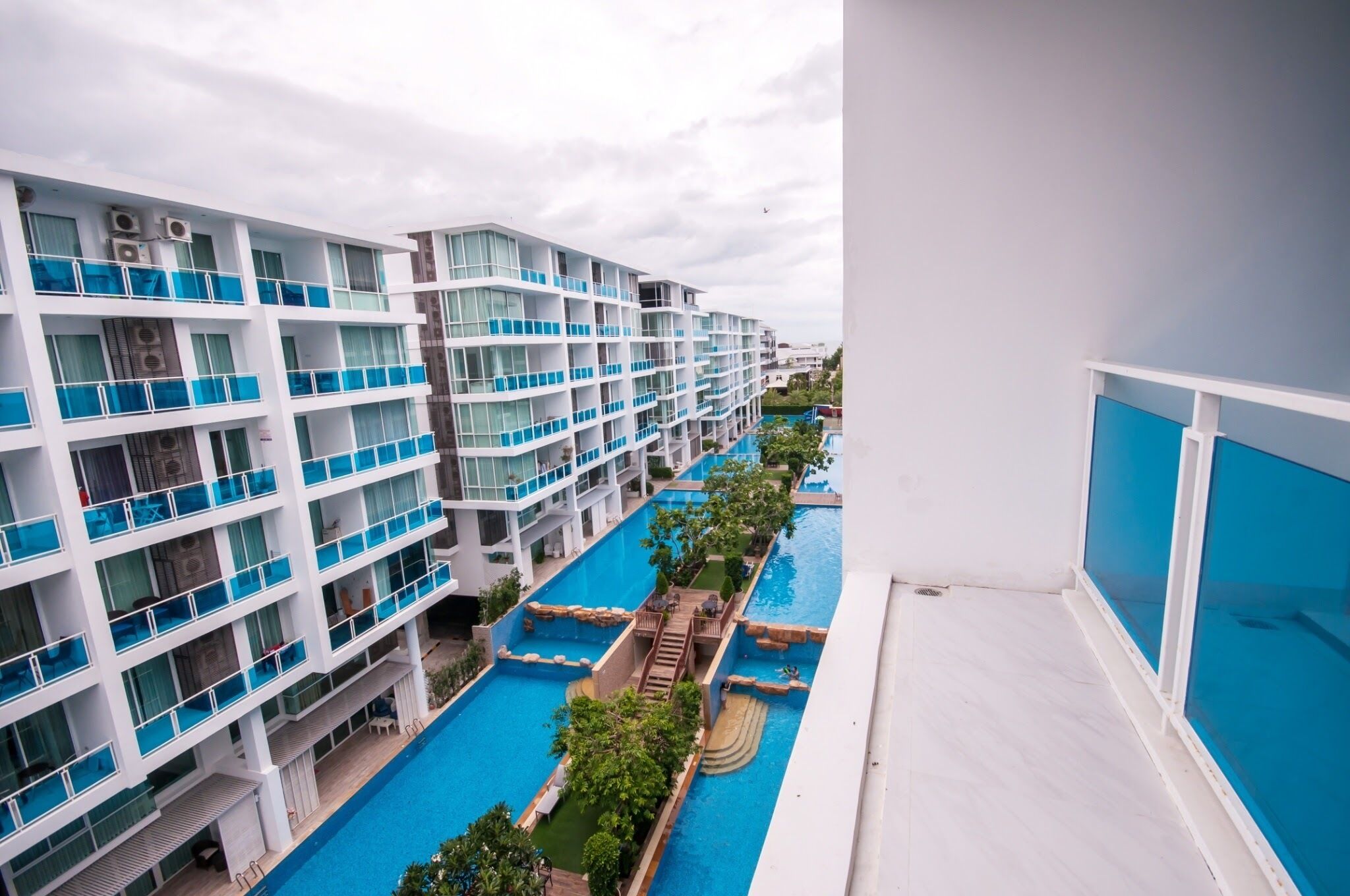 A multi-story hotel with balconies, a swimming pool, and a view of the surrounding area.