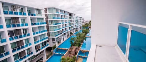 A multi-story hotel with balconies, a swimming pool, and a view of the surrounding area.