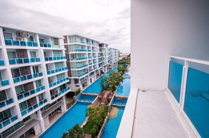 A multi-story hotel with balconies, a swimming pool, and a view of the surrounding area. - D603 Bright Cozy 2-bedroom apartment with Playground near Beach (Huahin)