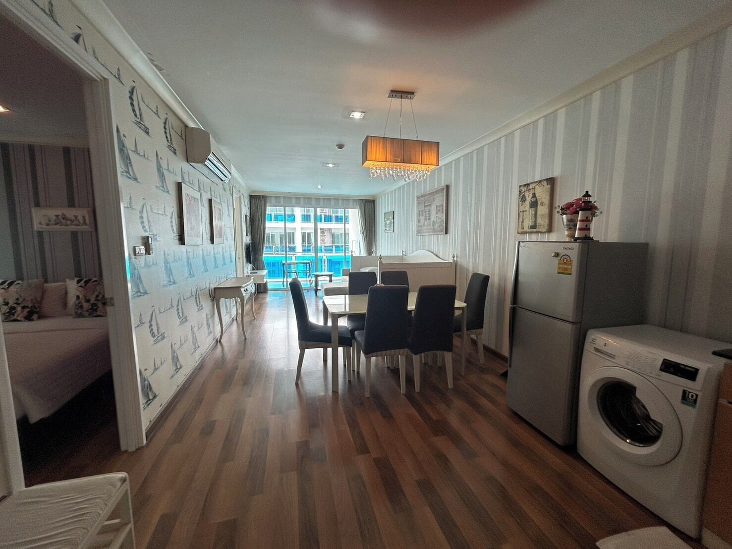 Eine moderne Küche mit Essbereich, einer Waschmaschine und Blick auf einen Balkon.