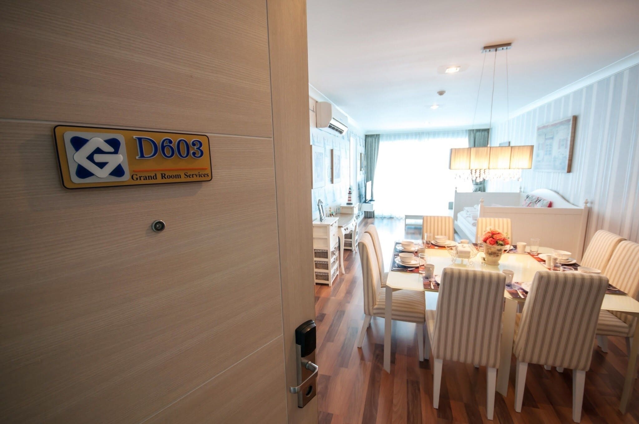 A hotel room with a dining area, a sign indicating room services, and a view of the city.