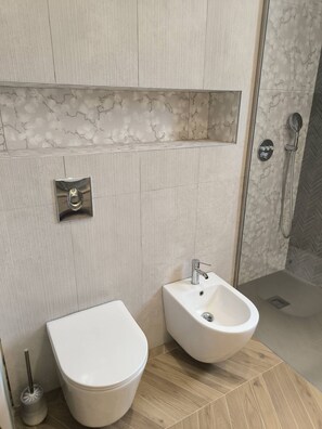 A modern bathroom with a toilet, bidet, and shower area. - Beautiful villa (Prunelli-di-Fiumorbo)