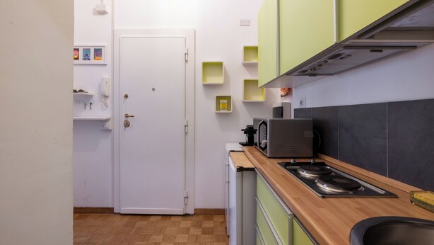 A compact kitchen with a white door, wooden countertop, and a microwave. - Charming suite with a view in the heart of Rome (Roma)