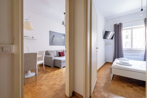 A modern hotel room with a bed, a sofa, a TV, and a window with curtains. - Charming suite with a view in the heart of Rome (Roma)
