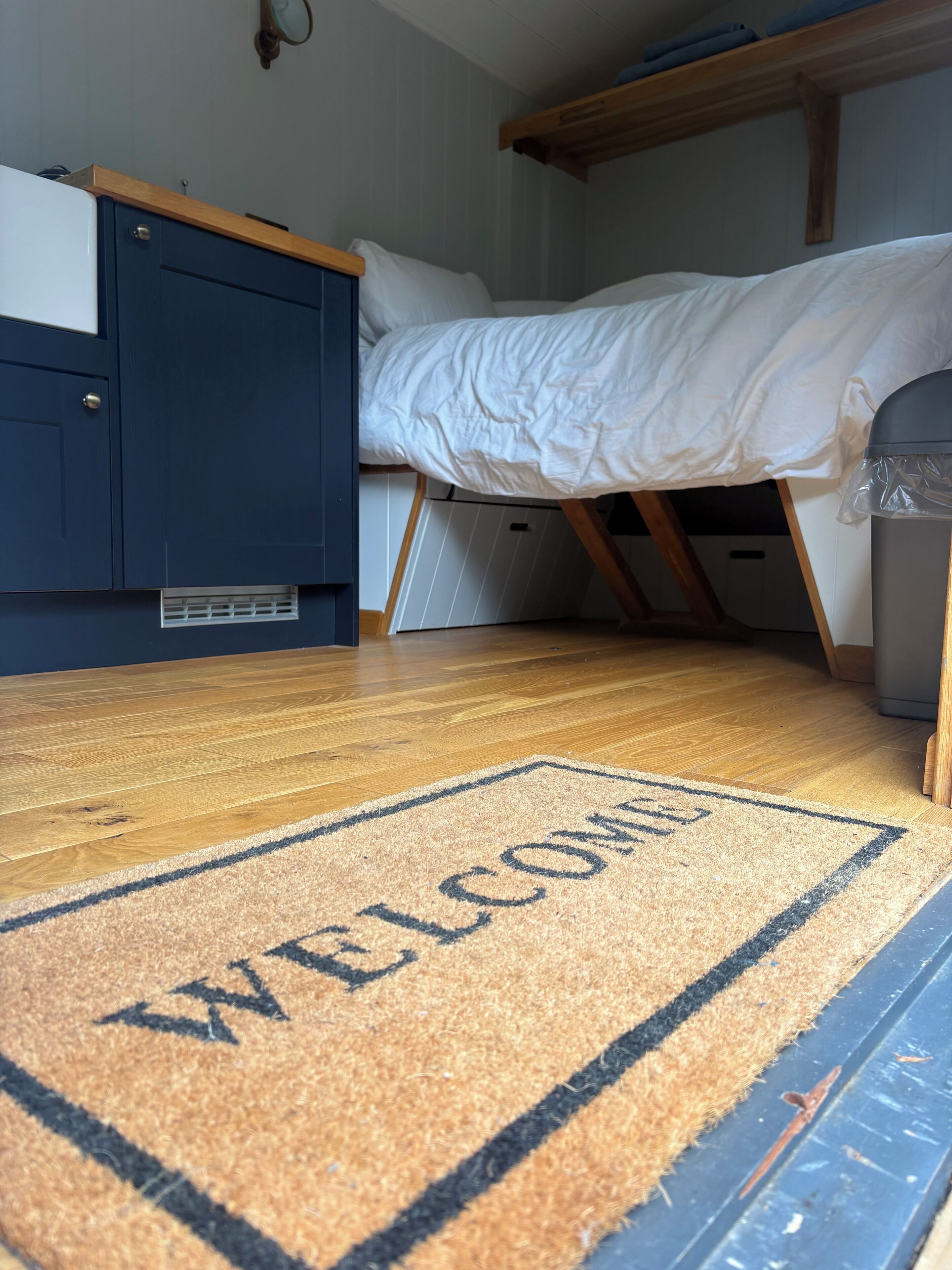 Une chambre avec un lit superposé, une armoire, un paillasson et une petite étagère sur laquelle sont posés quelques objets.