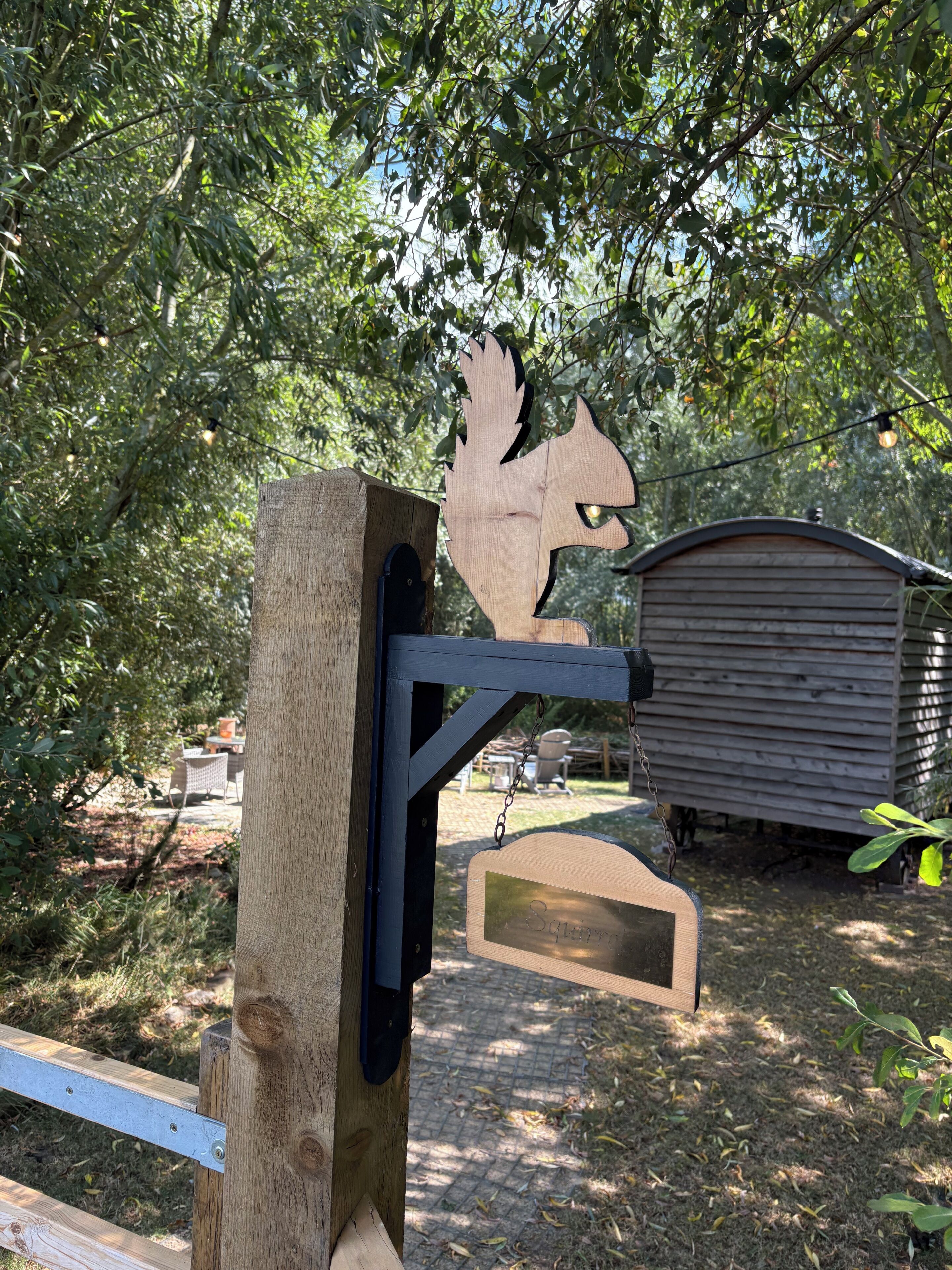 A wooden structure with a metal gate and a wooden sign that reads 'Squirrel.'
