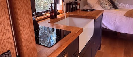 A compact kitchen with a wooden countertop, a sink, and a window with a view of trees.
