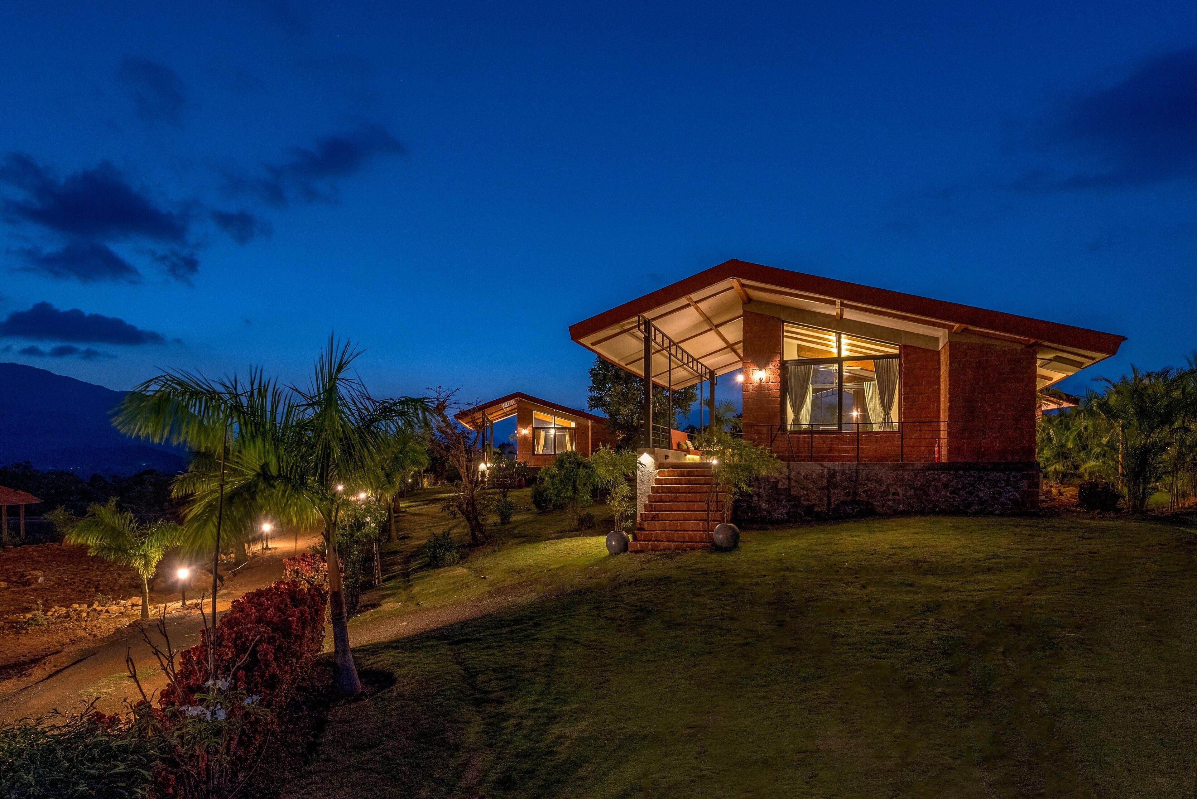 A modern house with a covered patio, a well-maintained lawn, and a mountain in the background.