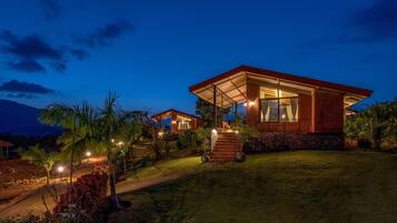 A modern house with a covered patio, a well-maintained lawn, and a mountain in the background.