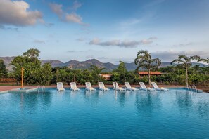 A swimming pool with lounge chairs and a mountain backdrop. - Satori Mulshi (Paud)