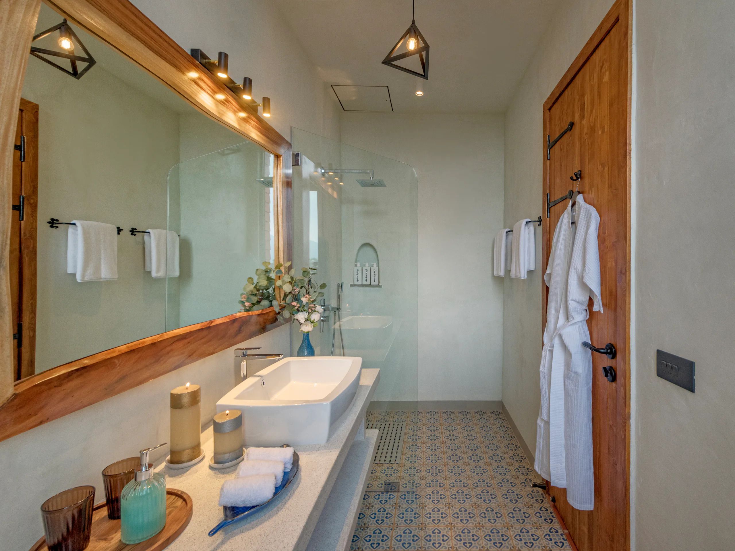 A modern bathroom with a large mirror, a freestanding bathtub, and a wooden door.