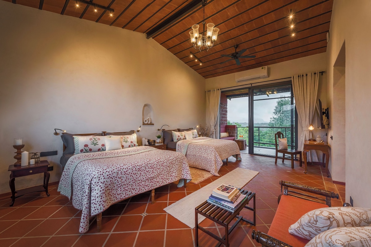 A bedroom with two beds, a ceiling fan, a chandelier, and a view of the outdoors through a large window.