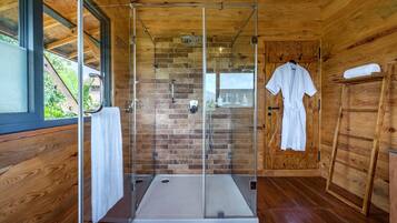 A modern bathroom with a glass-enclosed shower, wooden walls, and a wooden door with a towel rack.