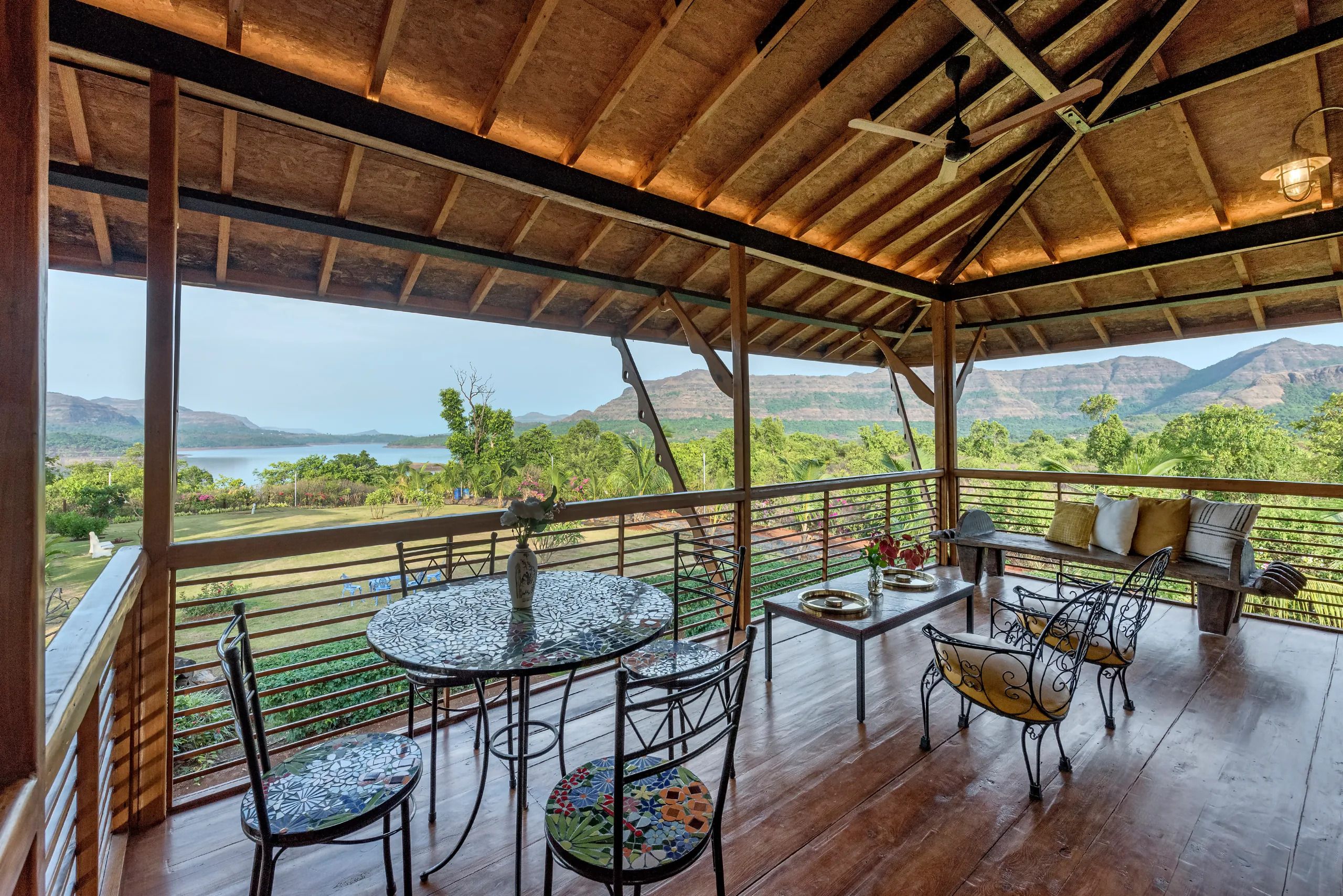 A covered outdoor seating area with a view of a mountainous landscape.
