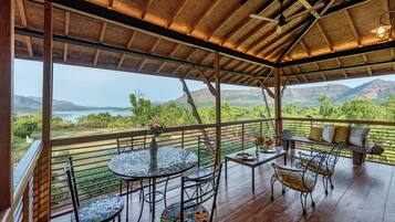 A covered outdoor seating area with a view of a mountainous landscape.