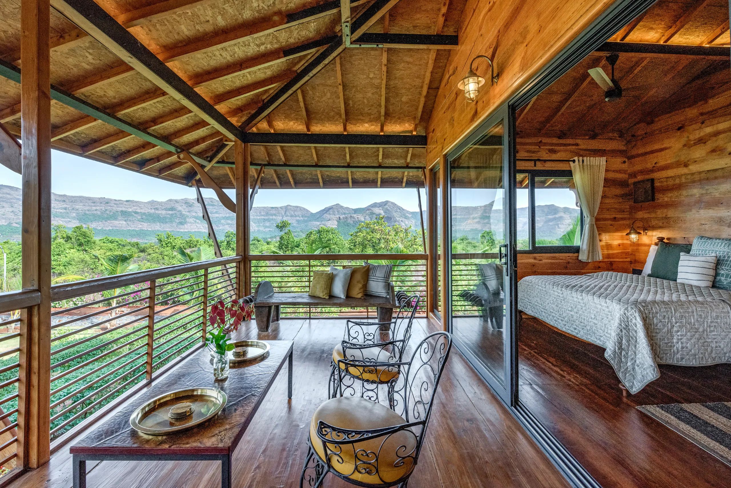 A wooden cabin with a balcony, a dining area with a table and chairs, and a bedroom with a bed.