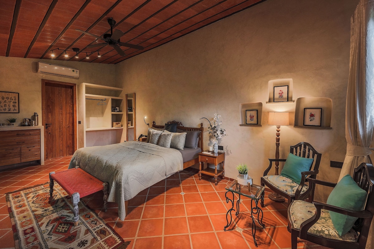 A bedroom with a bed, bedside tables, a chair, a small table, and a mirror.
