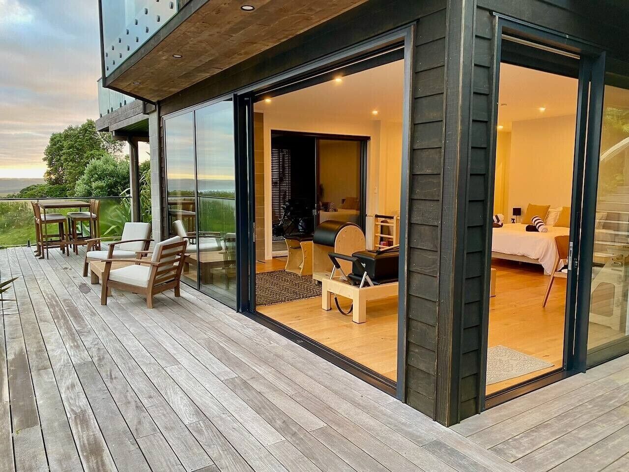 A modern house with a deck, a dining area, and a bedroom with a bed and a sofa.
