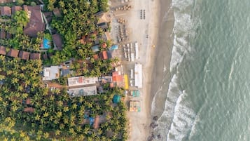Vista aérea de una zona costera con edificios, una playa y palmeras.