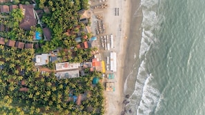 An aerial view of a coastal area with buildings, a beach, and palm trees.