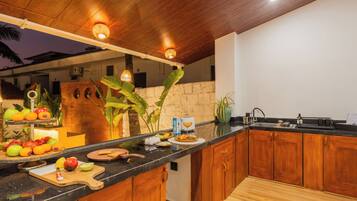 A kitchen with wooden cabinets, a black countertop, and a stone wall.