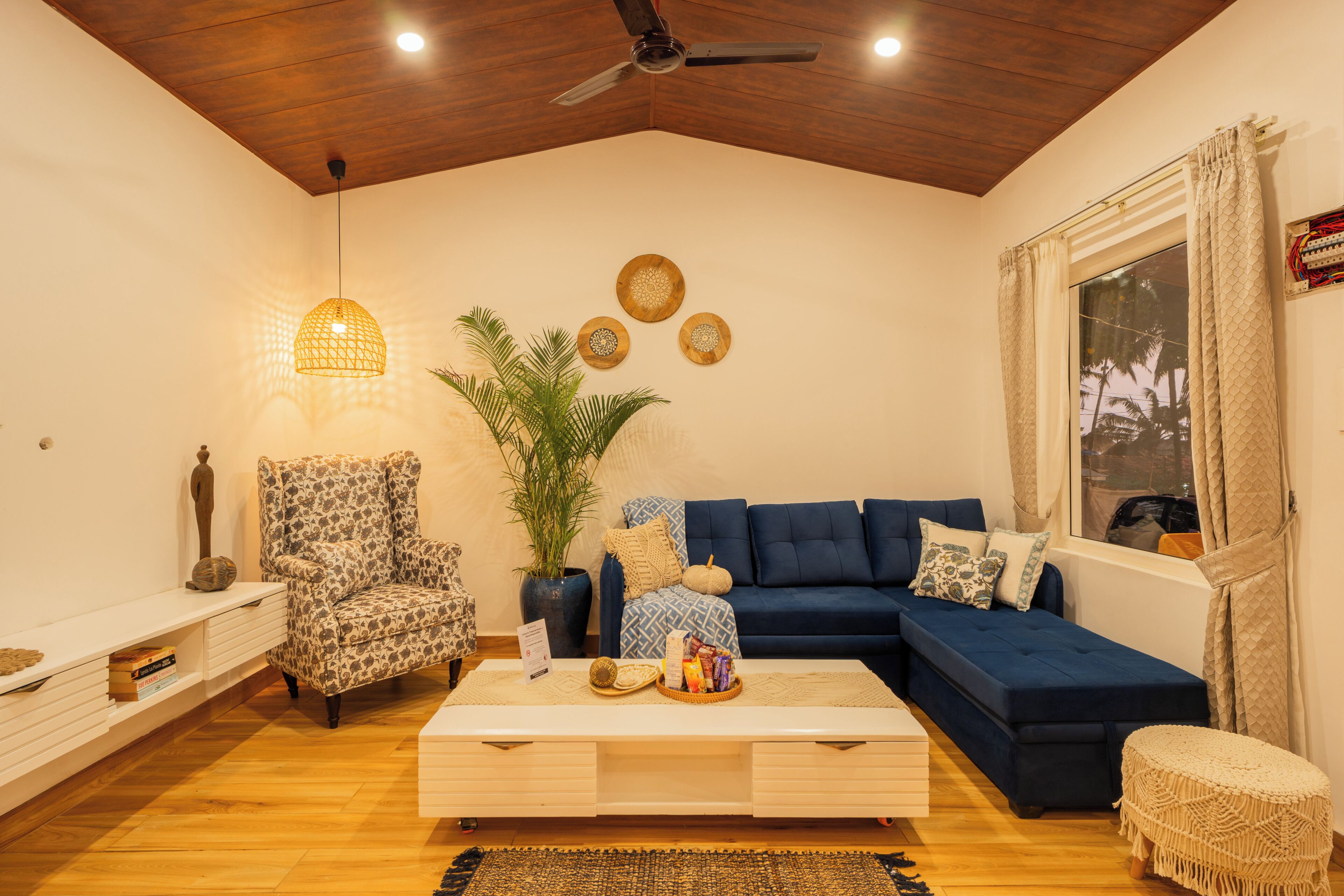 A living room with a sofa, armchair, coffee table, and a ceiling fan.