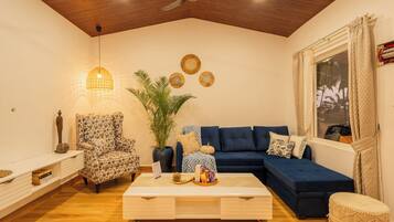 A living room with a sofa, armchair, coffee table, and a ceiling fan.