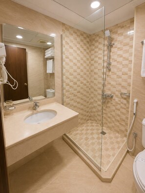 Un bagno con doccia vetrata, lavandino con specchio e toilette.