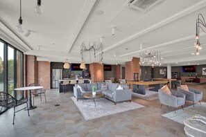 Ein geräumiger Wohnbereich mit Billardtisch, Sofas und einer Küche im Hintergrund.