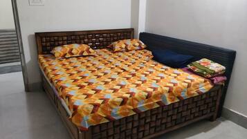Uma cama com colcha estampada, cabeceira e travesseiro sobre um chão de azulejos.
