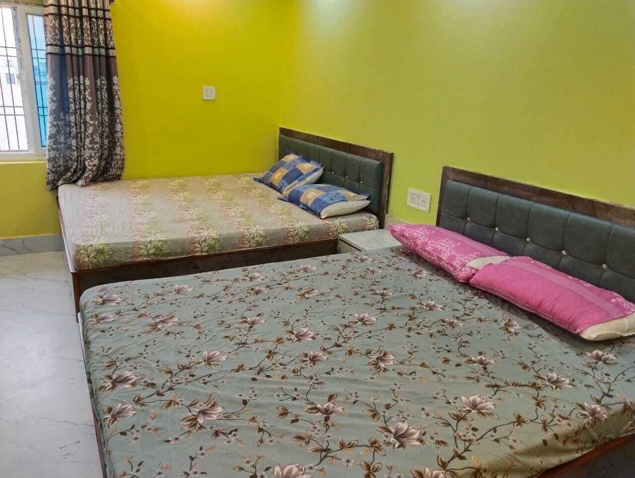 Una habitación con dos camas, una con cubrecama floral y la otra sin adornos.