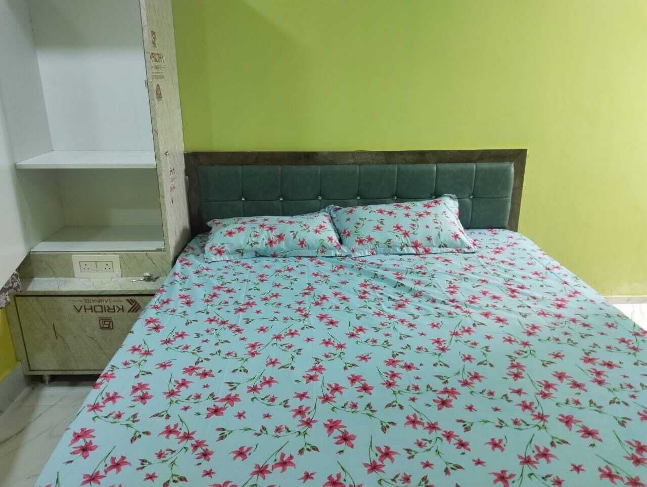 A bed with a floral bedspread, a headboard, and a bedside cabinet.