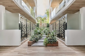 Ein modernes Interieur mit einer zentralen Treppe, umgeben von Pflanzen, Holzböden und einem Glasgeländer.