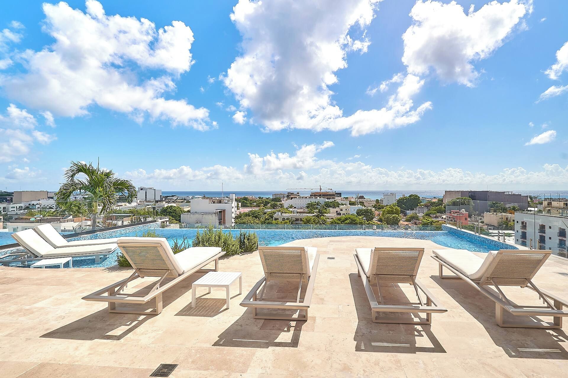 A rooftop pool area with lounge chairs and a view of the cityscape.