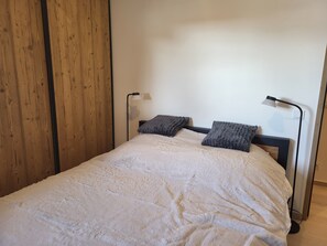 Ein Einzelbett mit weißer Daunendecke, zwei Kissen und zwei Nachttischlampen.