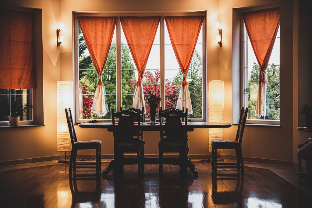 A dining area with a round table, four chairs, and a vase of flowers.