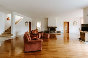 Ein geräumiges Wohnzimmer mit Kamin, einer Couch und einem Fernseher.