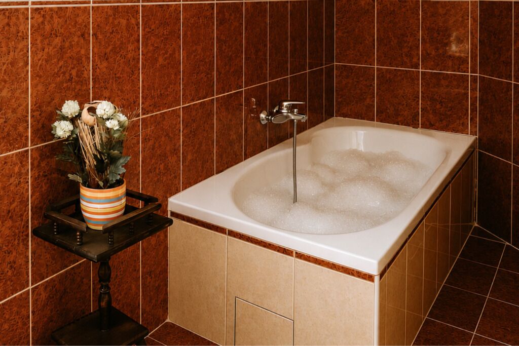 Ein Badezimmer mit einer Badewanne, einer kleinen Ablage mit einer Vase und braunen Fliesenwänden.