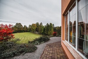 Ein Gebäude mit einem gepflasterten Weg, der zu einer grünen Fläche mit Bäumen und Sträuchern führt.