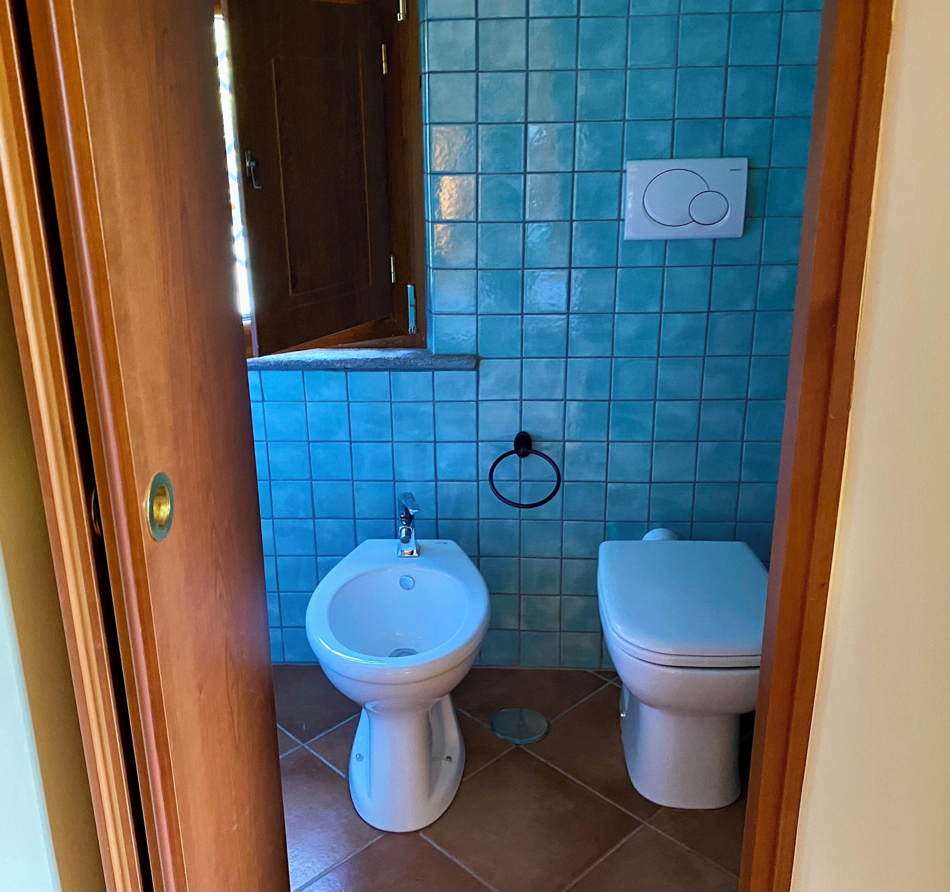 Une salle de bain équipée d’un bidet, de toilettes et d’un mur carrelé.