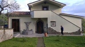 A house with a stone facade, a wooden door, a stone staircase, and a small garden.