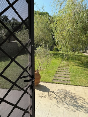 A garden with a paved walkway, a potted plant, and a fence.